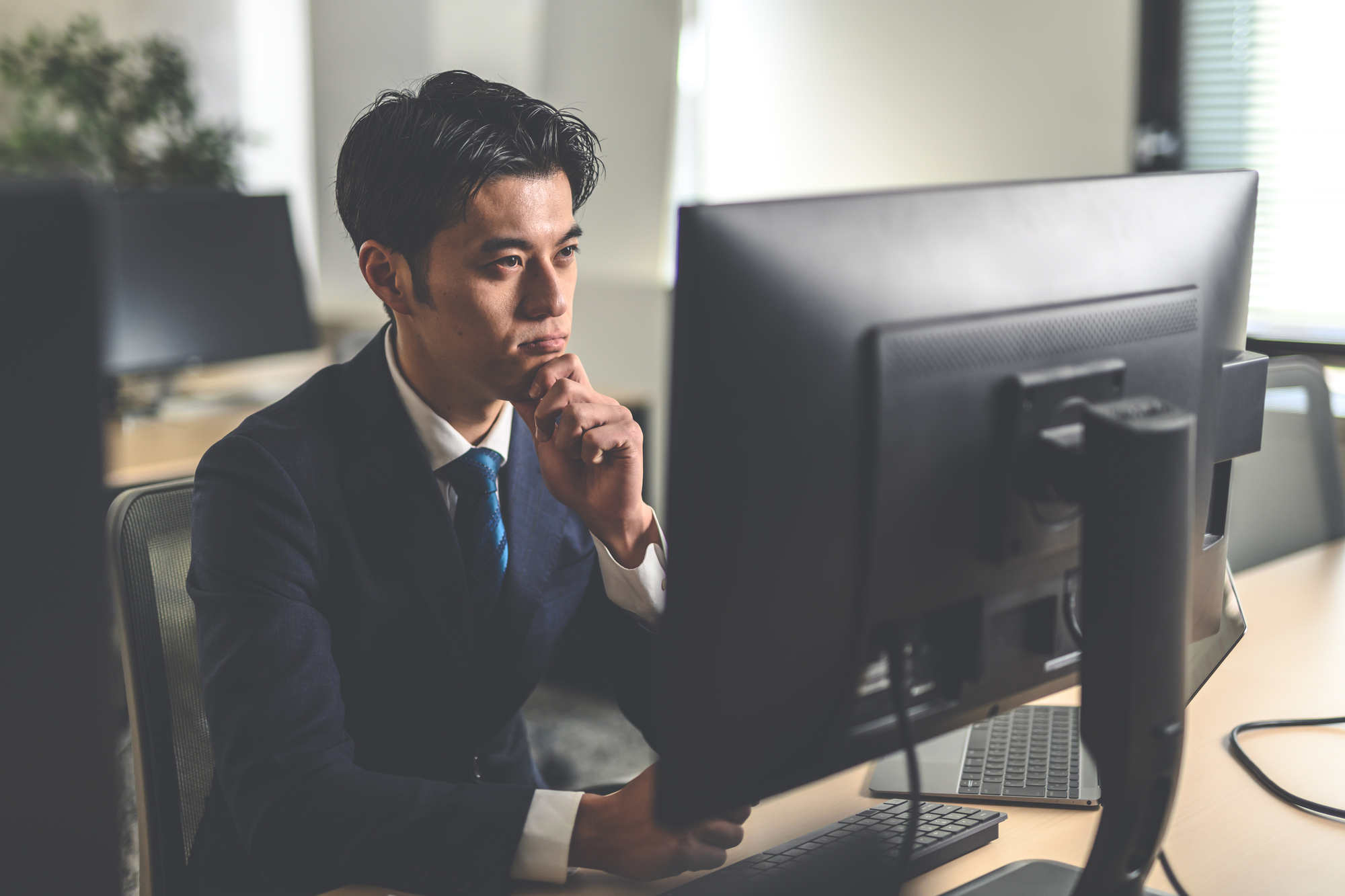 パソコンを見ながら悩むビジネスパーソン