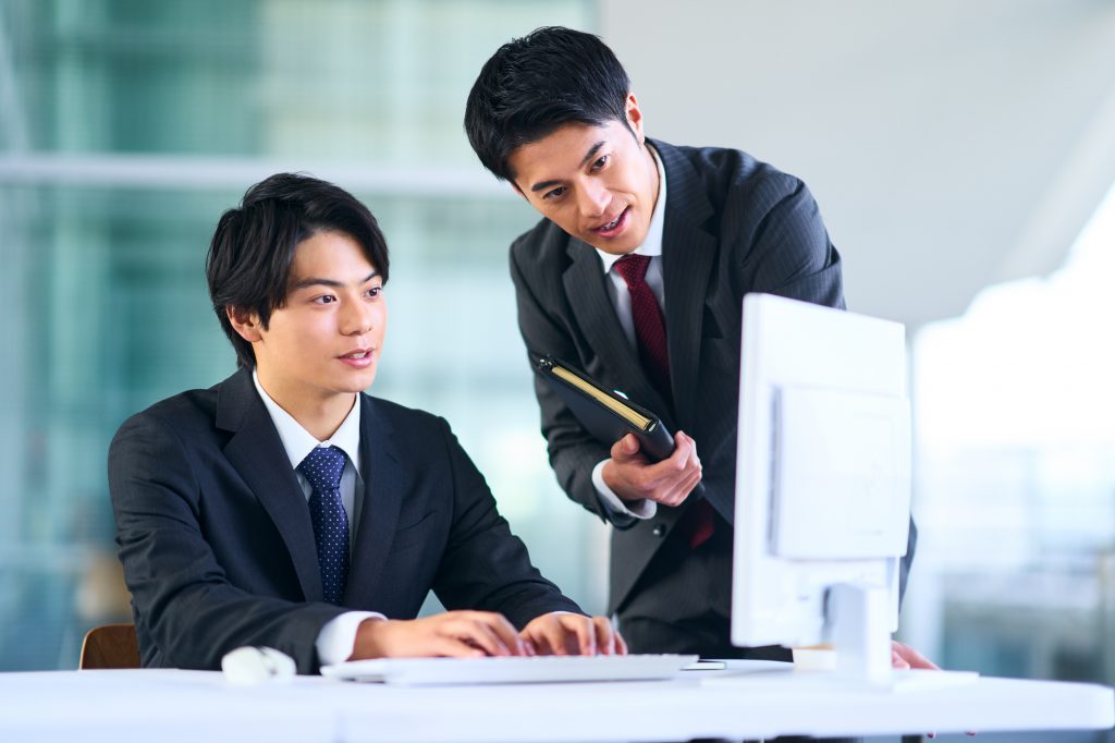 パソコンを見ながら会話する2人のビジネスパーソン