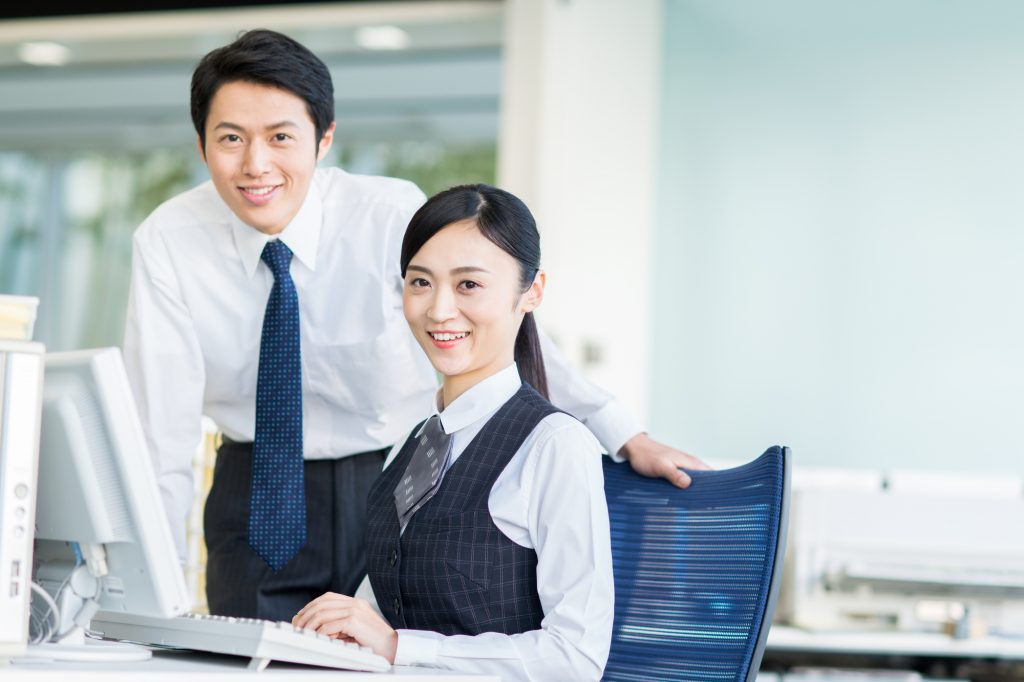 パソコンの前で笑顔を浮かべる2人のビジネスパーソン