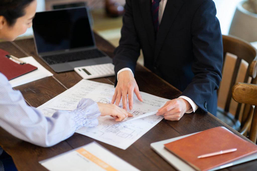 デスクに資料とパソコンを置いてミーティングする2人のビジネスパーソン
