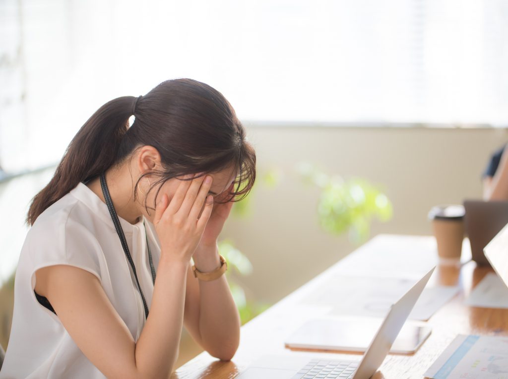 パソコンを前に頭を抱えながら悩むビジネスパーソン
