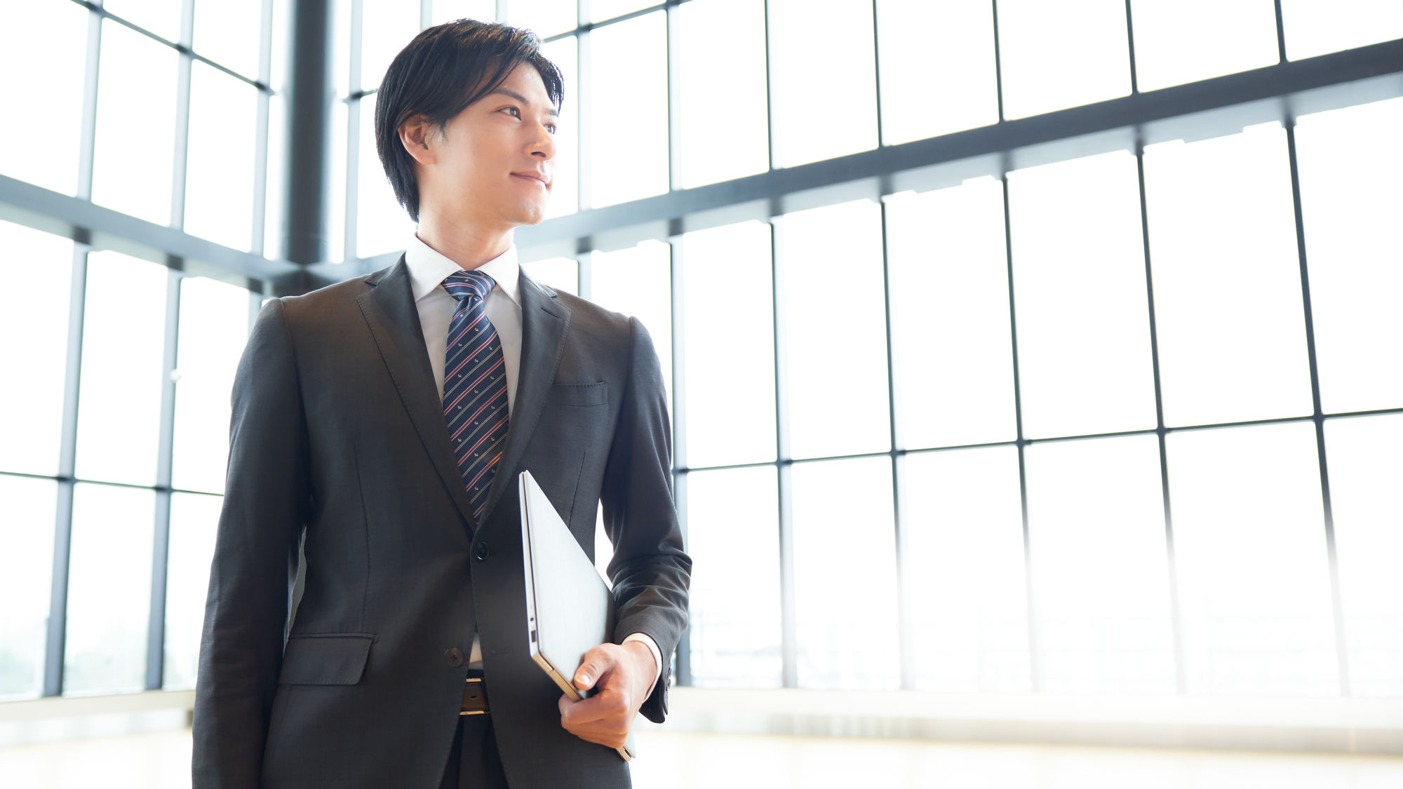 パソコンを持って遠くを見つめるビジネスパーソン