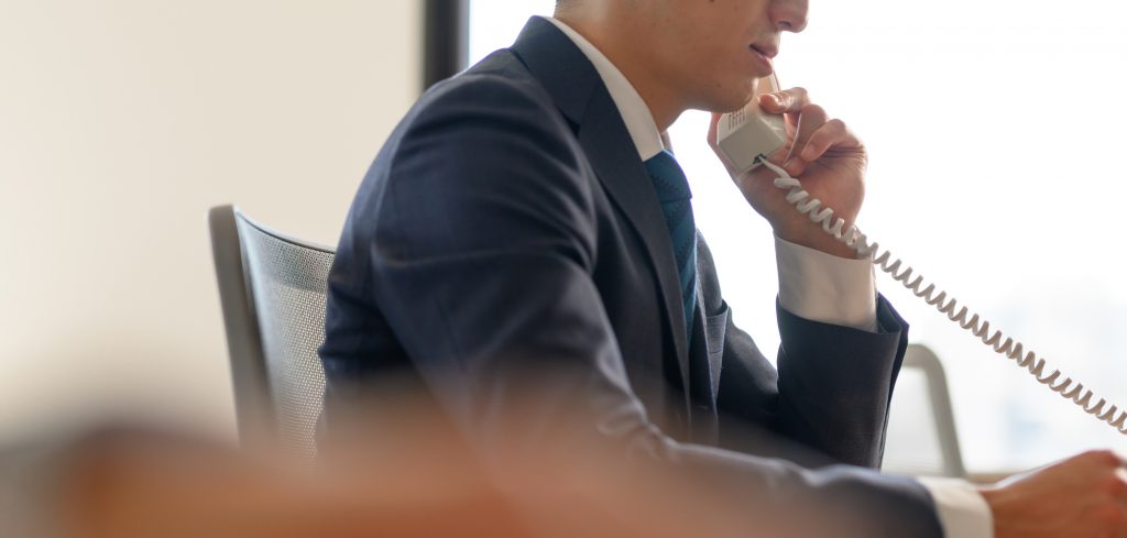 デスクに座り電話をかけるビジネスパーソン