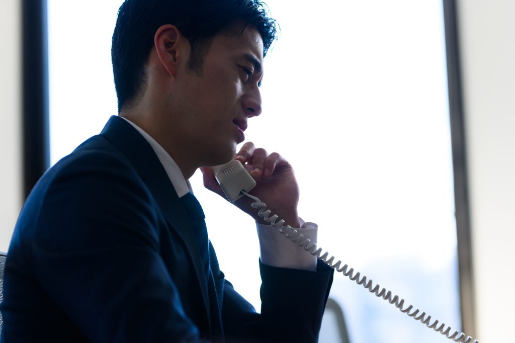 電話をしながら悩んだ顔をするビジネスパーソン