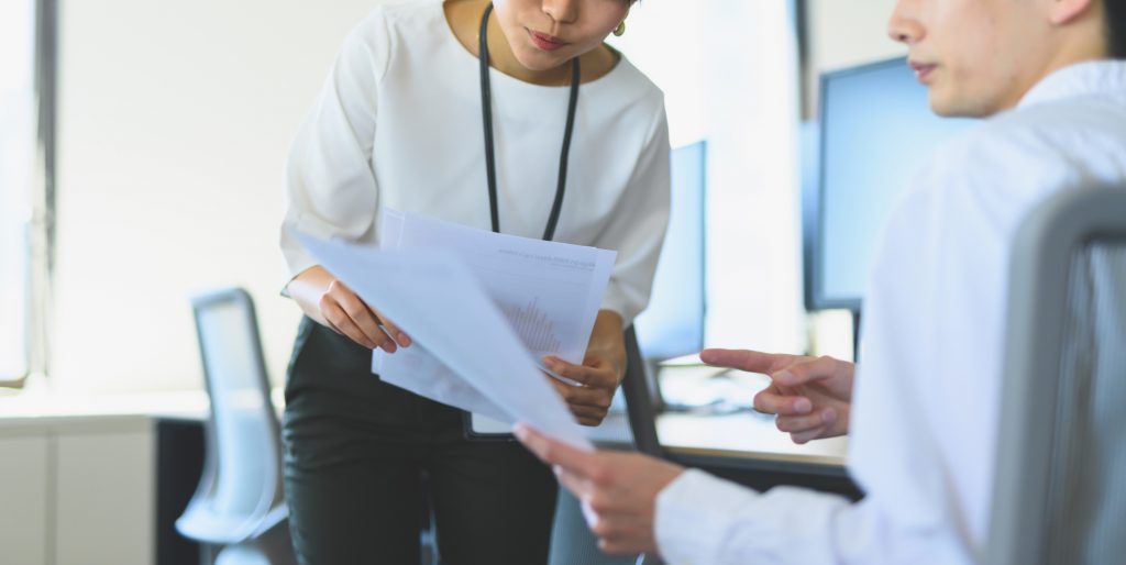資料を手に話をする2人のビジネスパーソン