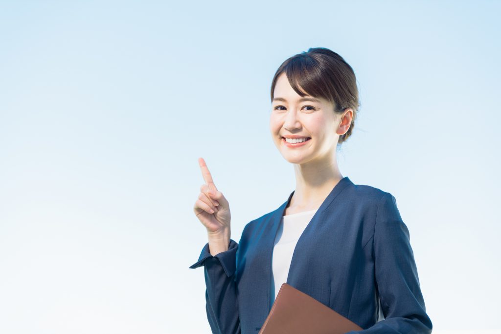 書類を持ちながら人さし指を立てる女性