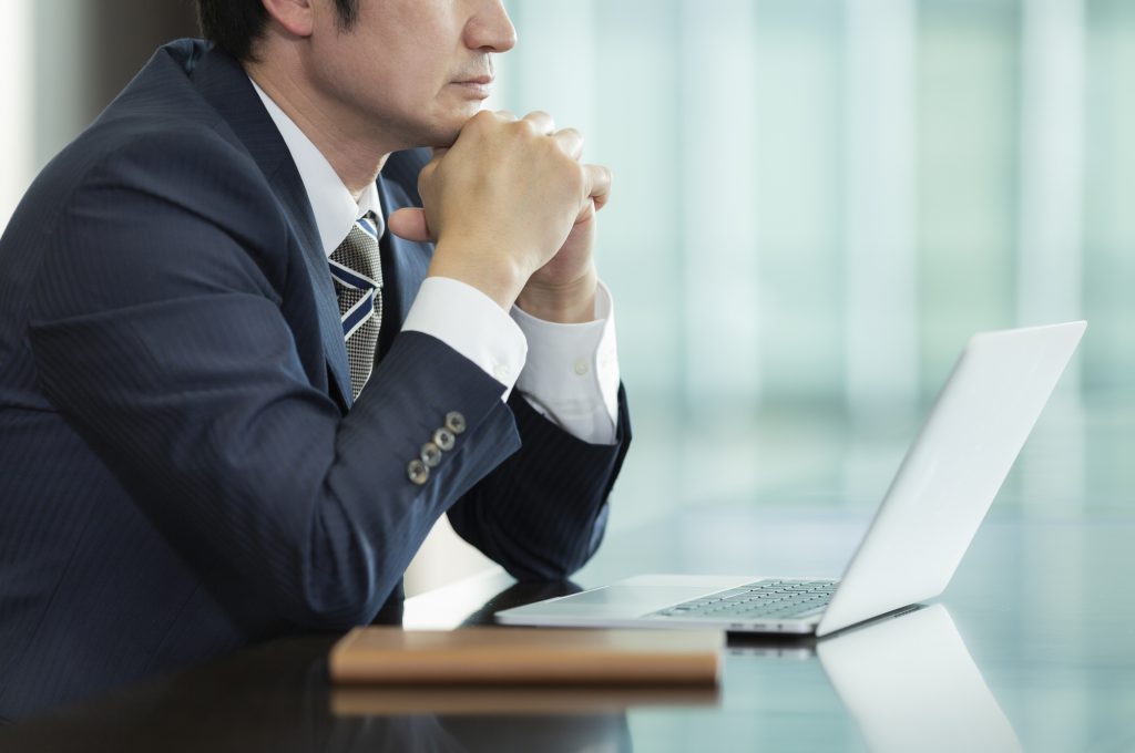 パソコンを見ながら悩むビジネスパーソン
