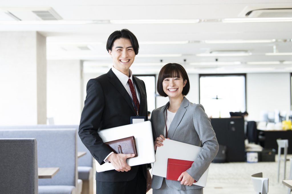 笑顔で立つ2人のビジネスパーソン