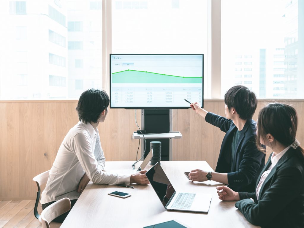 モニターを見ながらミーティングする3人のビジネスパーソン