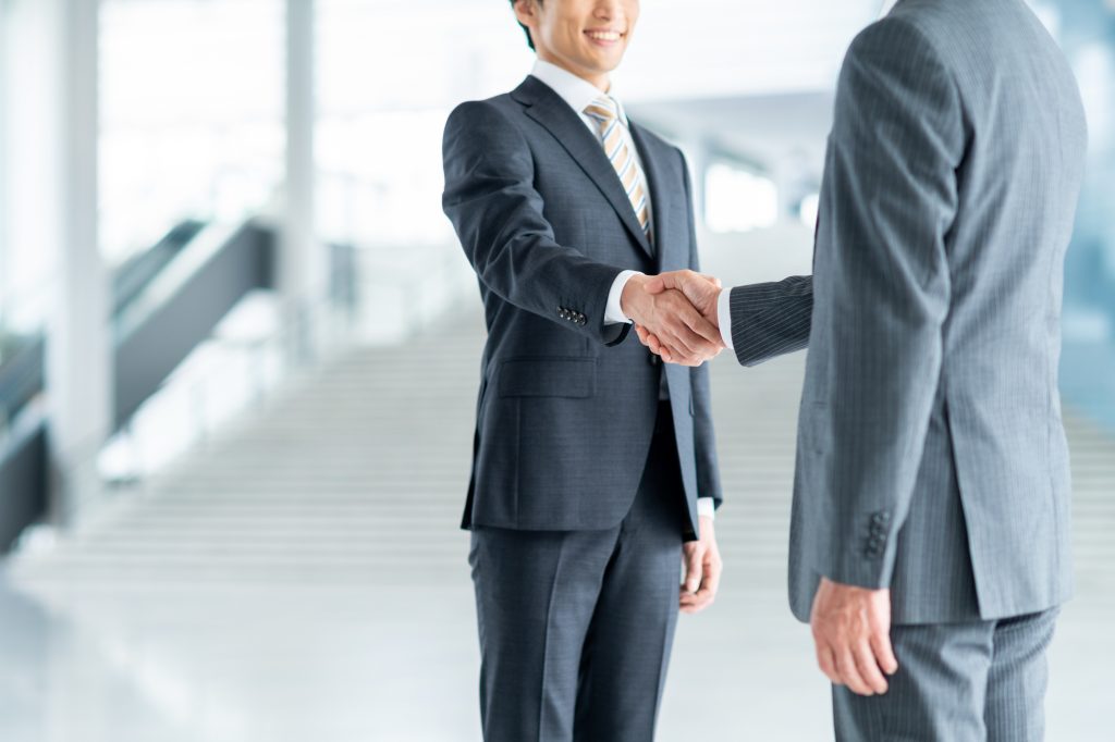 オフィス前で握手するビジネスパーソン