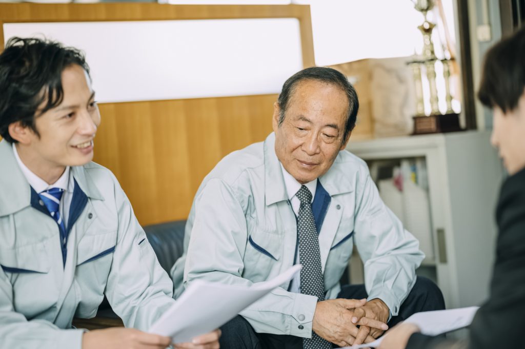 ソファに座り資料を片手に打ち合わせする3人のビジネスパーソン