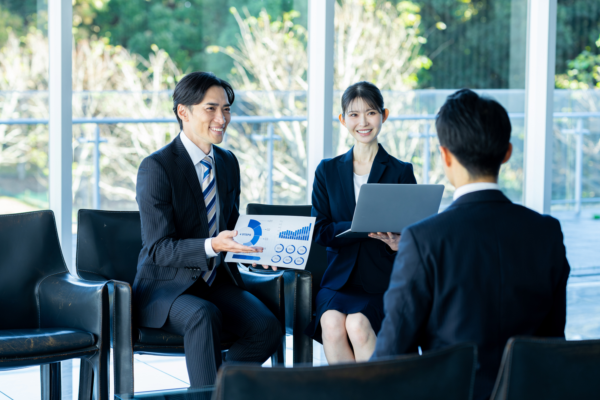 資料を手に商談するビジネスパーソン