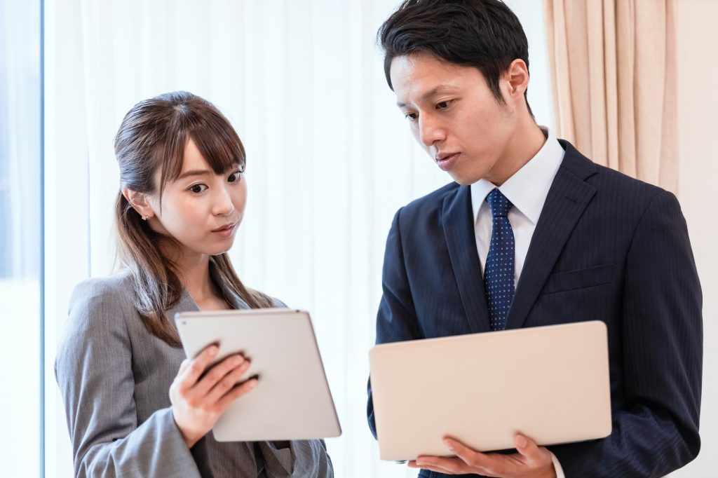 資料を手に会話するビジネスパーソン2人