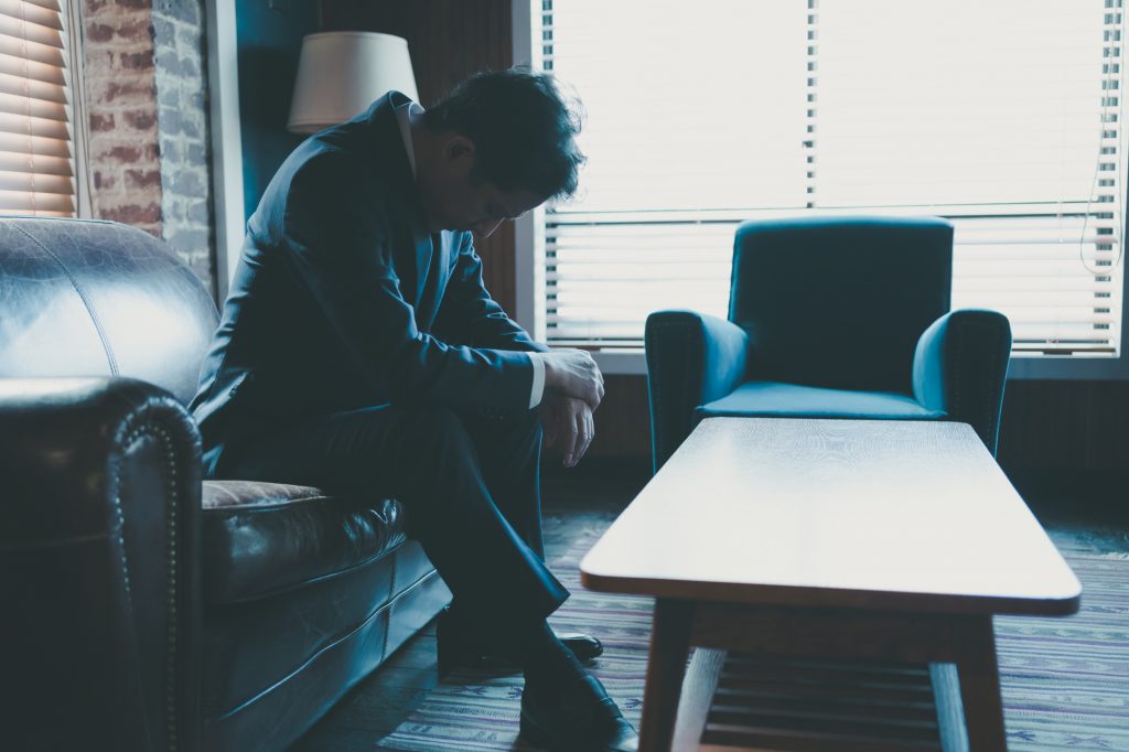 オフィスの応接室に座り悩むビジネスパーソン