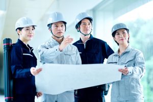 設計図を持ちながら話す4人のビジネスパーソン