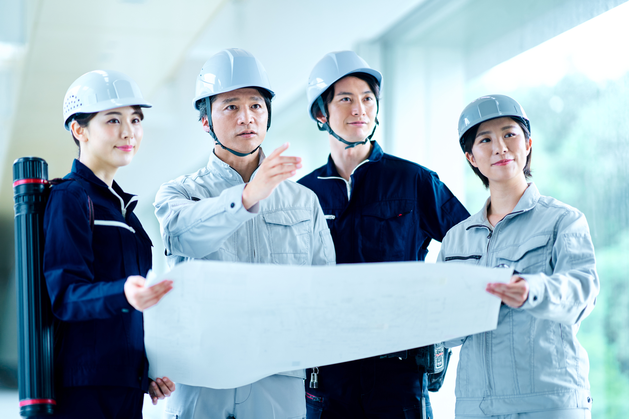 設計図を持ちながら話す4人のビジネスパーソン