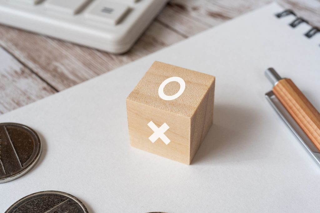 デスクに◯と×のブロックとコイン、ノートとペンが置かれた様子