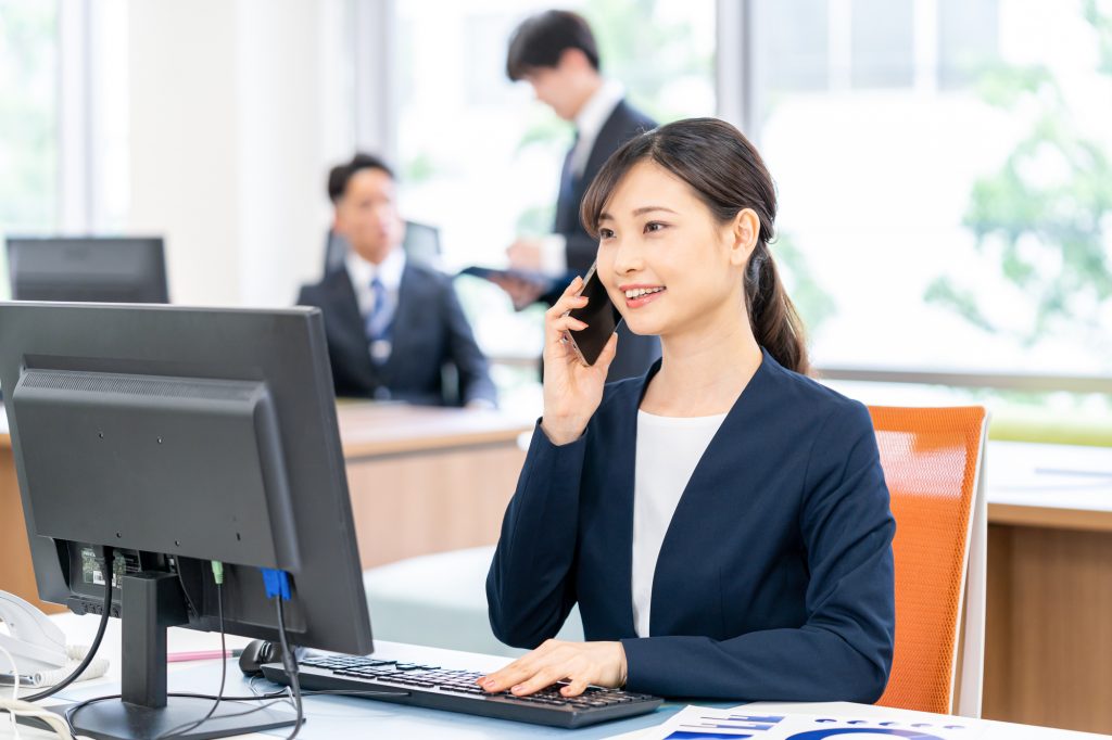 パソコンの前で電話をするビジネスパーソン
