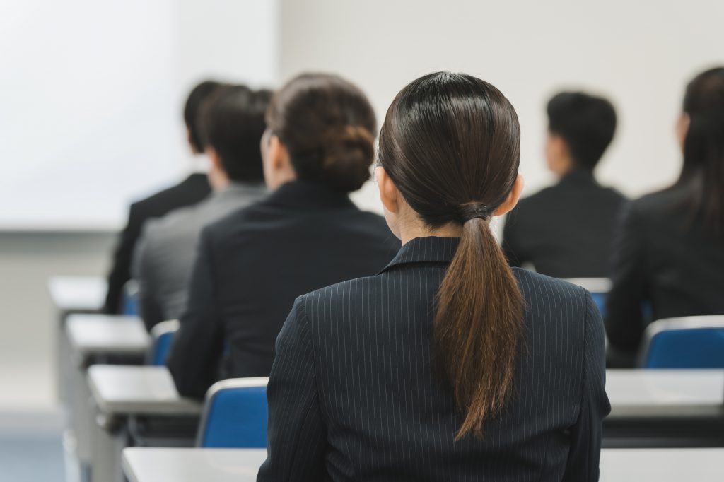 会議室で話を聞くビジネスパーソン