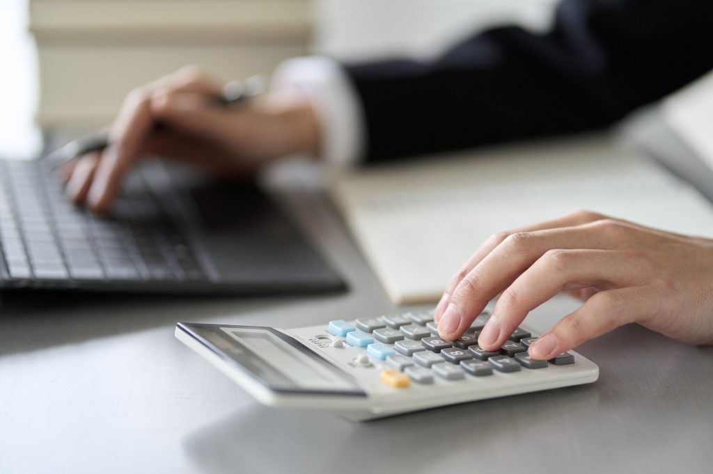 電卓を使用しながらパソコン作業をするビジネスパーソンの手元
