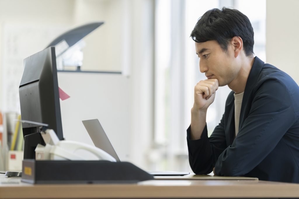パソコンを見ながら考えるビジネスパーソン