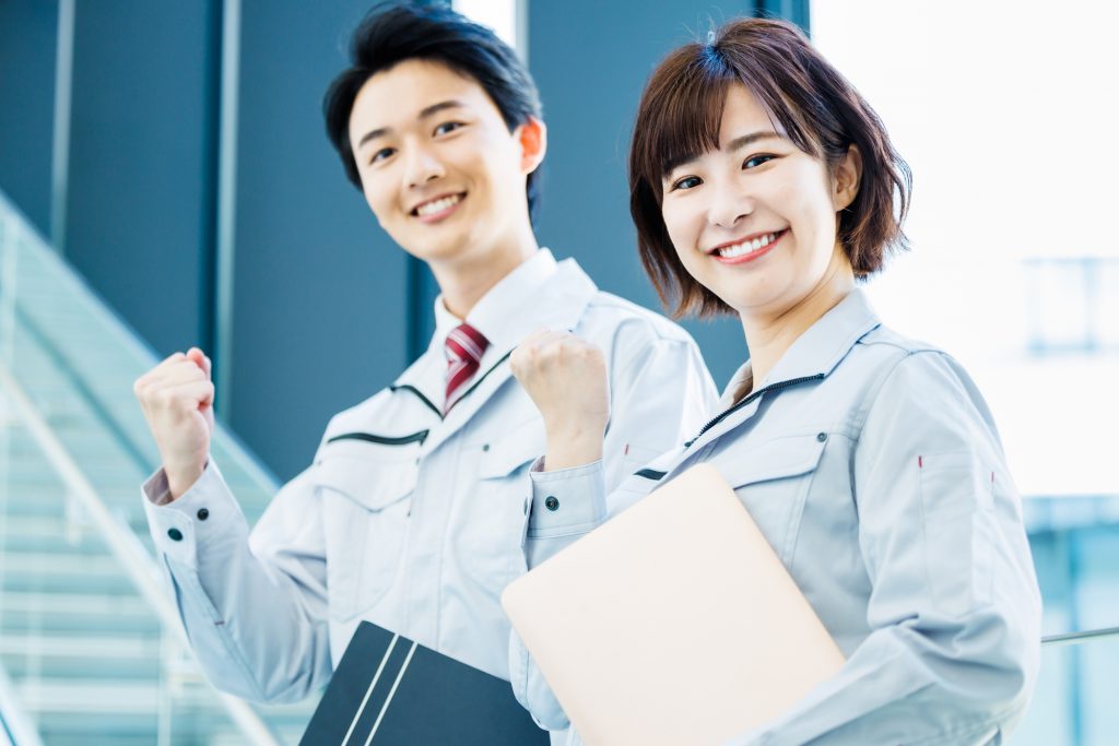 笑顔でガッツポーズをする作業着を着た2人のビジネスパーソン