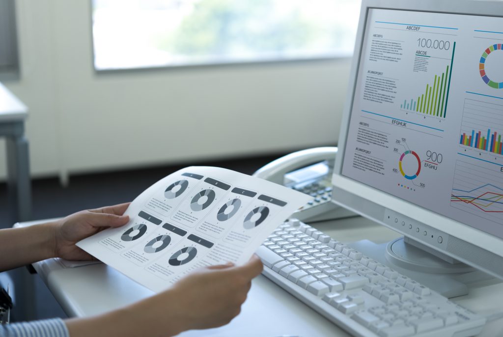 パソコン作業をしながら資料を見るビジネスパーソンの様子