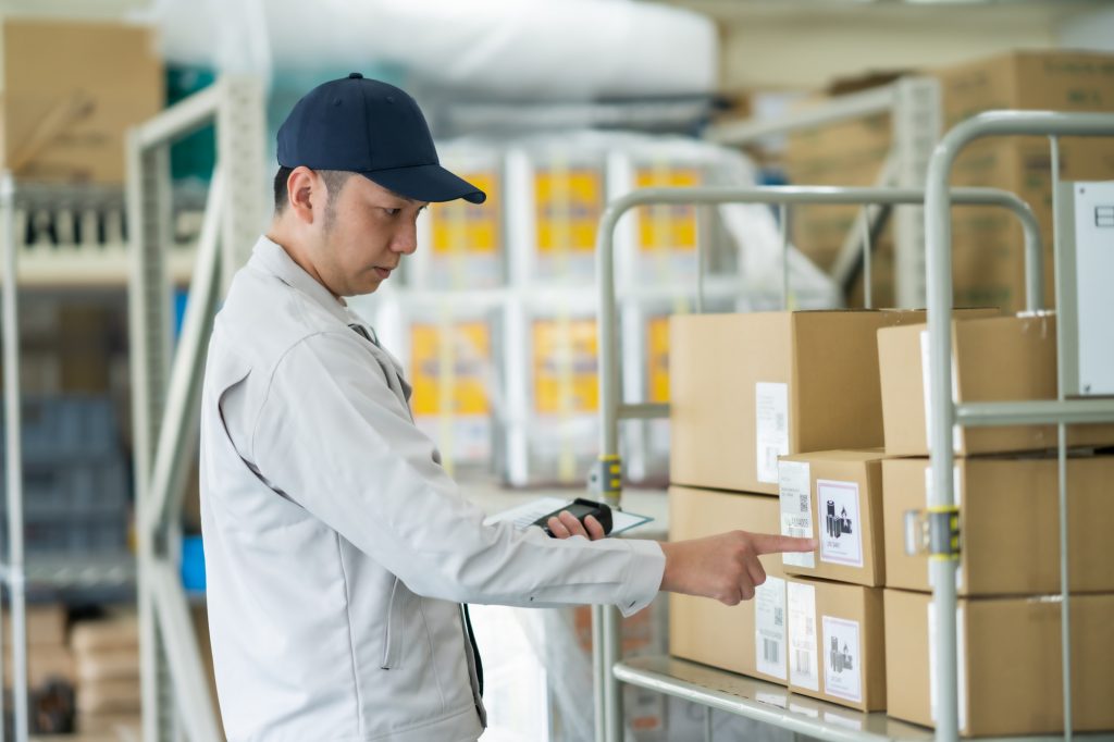 倉庫に置かれたダンボールを確認するビジネスパーソン