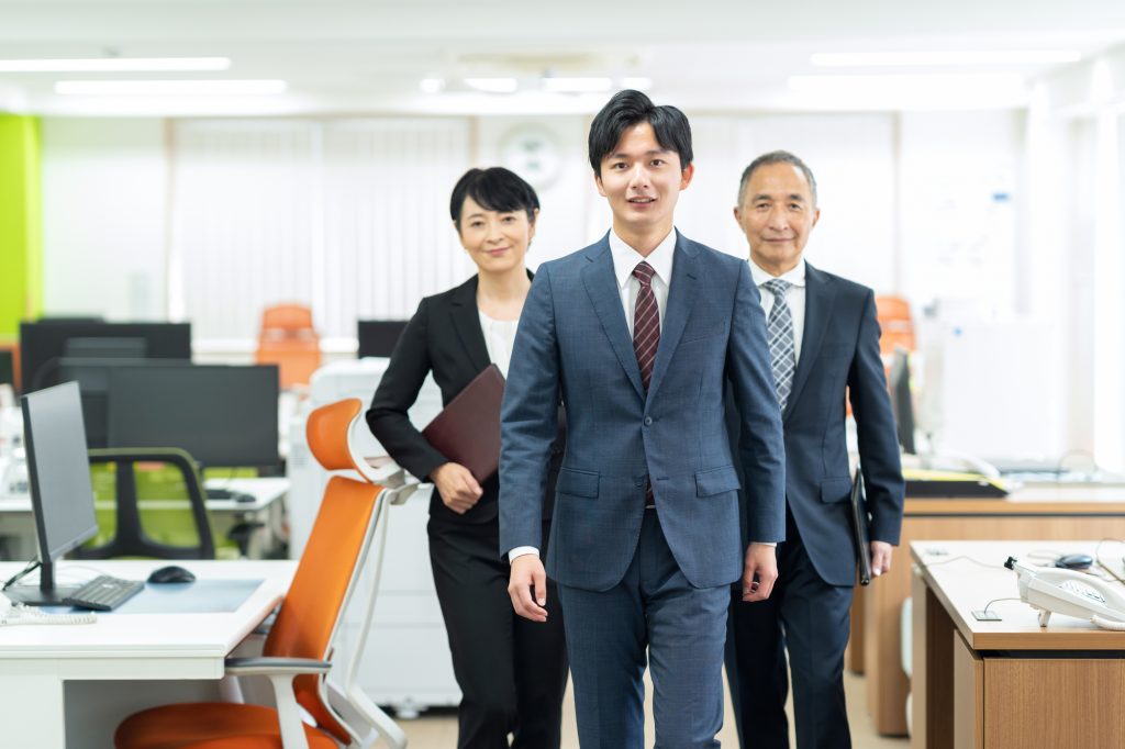 オフィスに笑顔で立つ3人のビジネスパーソン