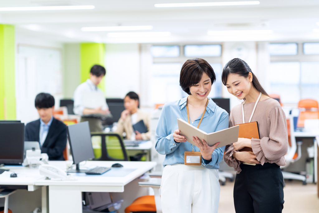 オフィスで資料を見ながら話す2人のビジネスパーソン