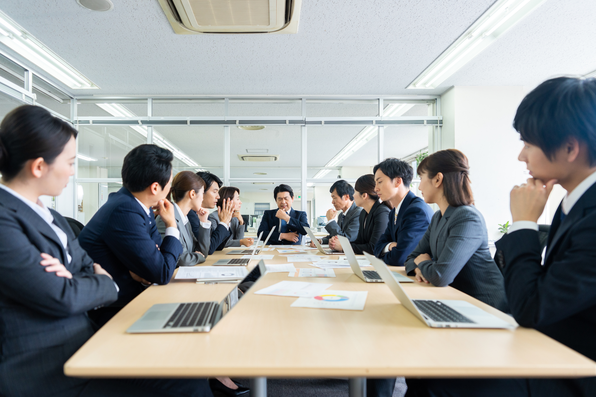 会議室で考え込む大勢のビジネスパーソン
