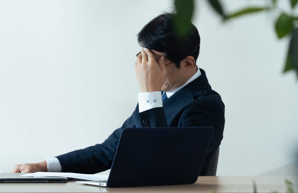 デスクに座り悩むビジネスパーソン