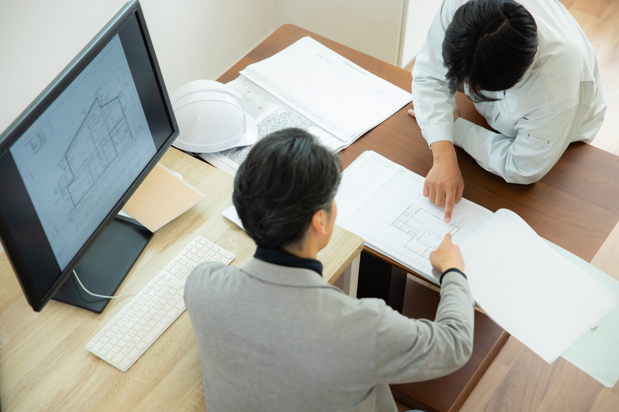 資料を見ながら話す2人のビジネスパーソン