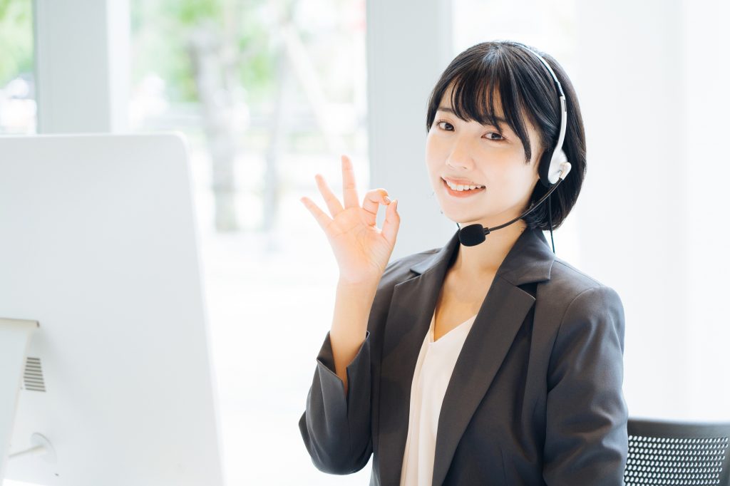 指で丸マークを作るヘッドセットをつけた女性
