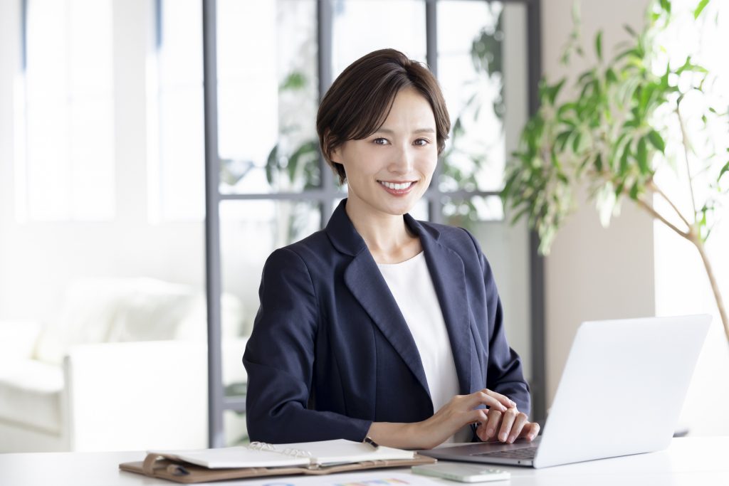 パソコンと手帳を置いたデスクに座ったビジネスパーソン