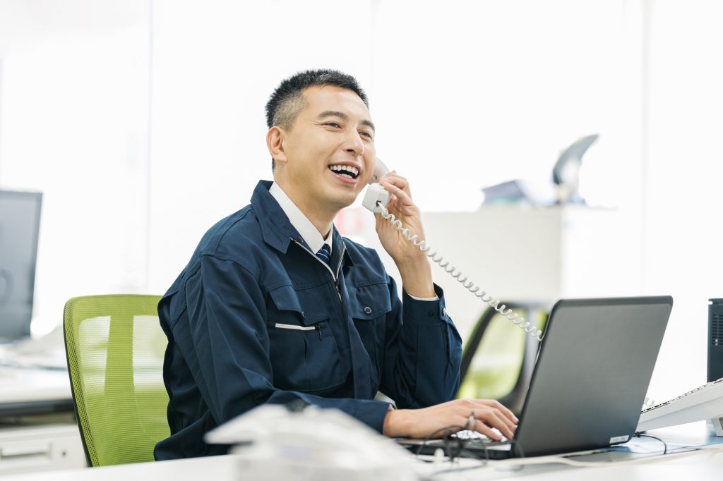 パソコン作業をしながら電話するビジネスパーソン