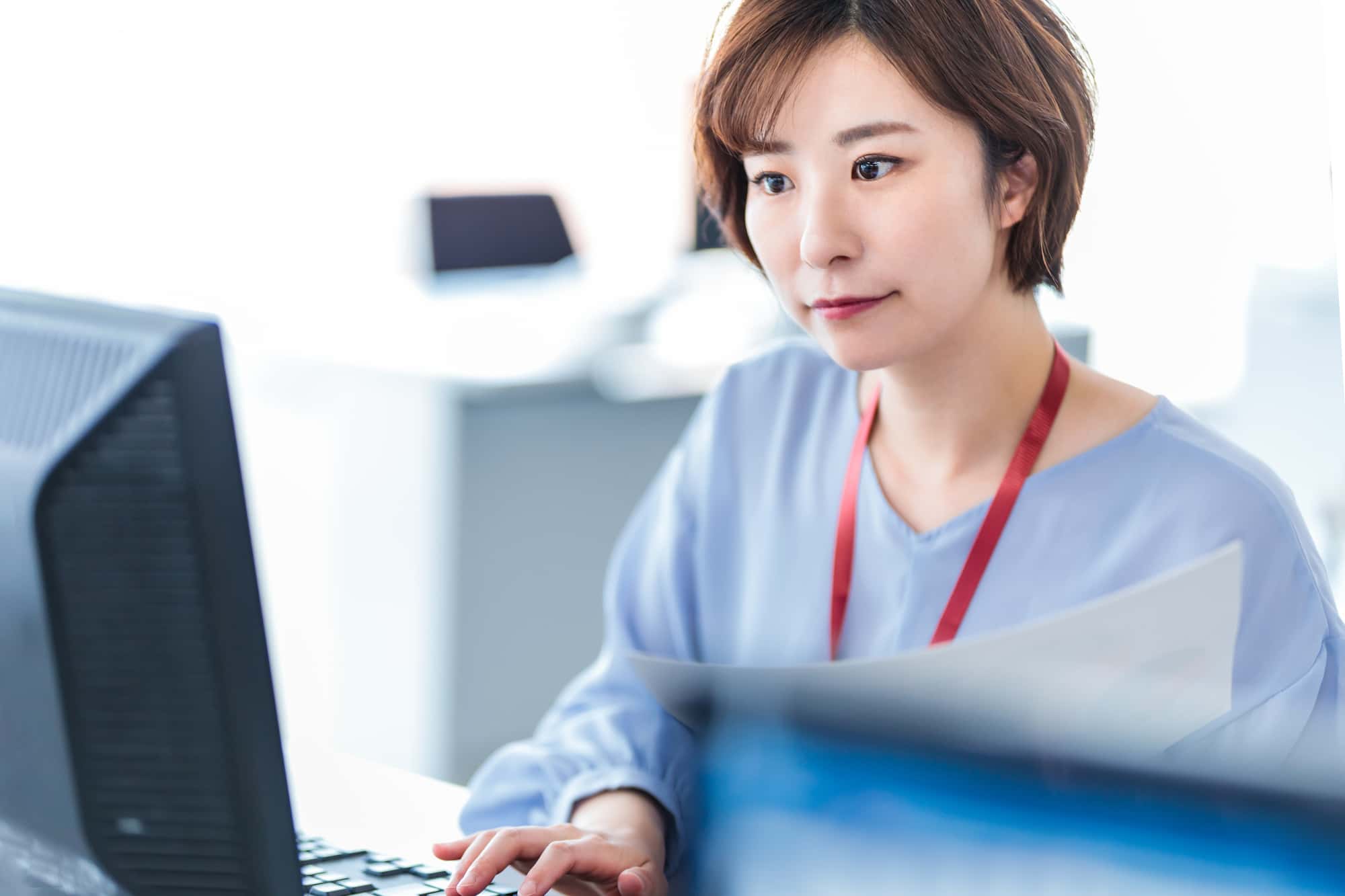 資料を見ながらパソコン作業をするビジネスパーソン