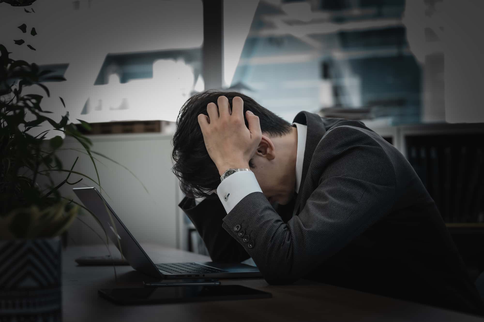 オフィスのデスクで頭を抱える男性