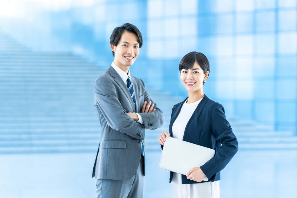 笑顔で立つ2人のビジネスパーソン