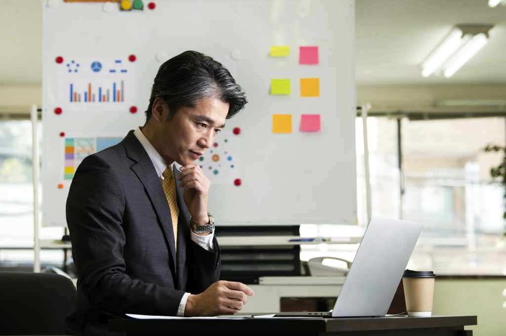 パソコンを見ながら考え込むビジネスパーソン