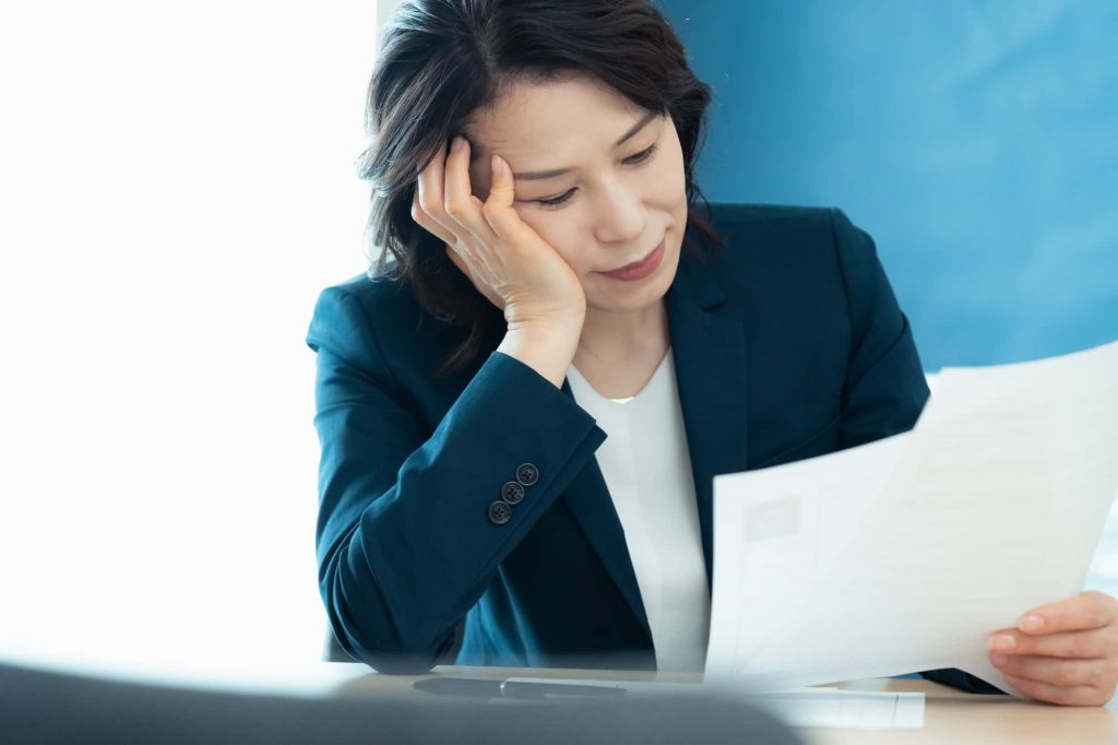 資料を見て悩むビジネスパーソン
