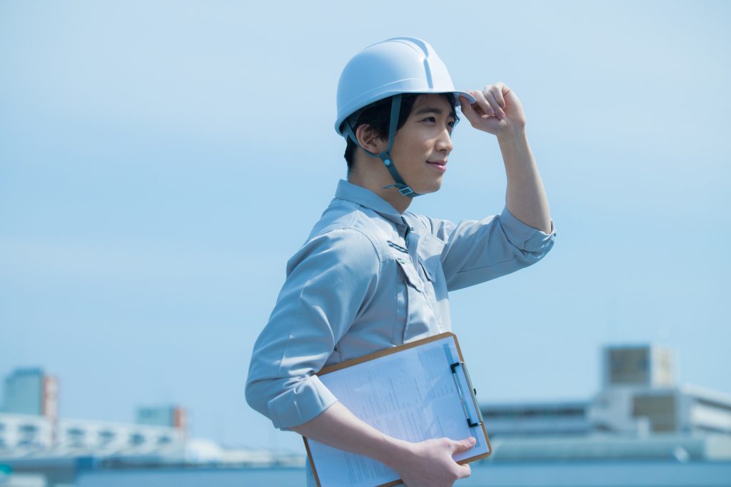 ヘルメットに手をかける作業服を着たビジネスパーソン
