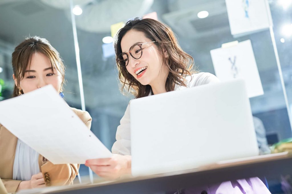 資料を見ながら話す2人のビジネスパーソン