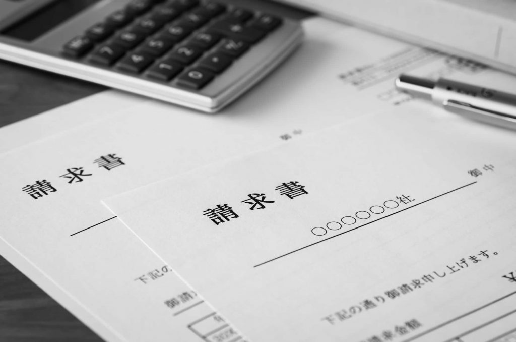 請求書と電卓、ペンが置かれている様子