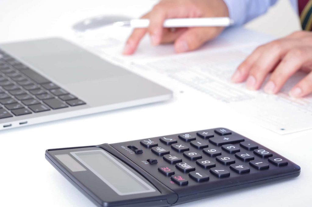 電卓とパソコンを置いて資料を確認するビジネスパーソンの手元