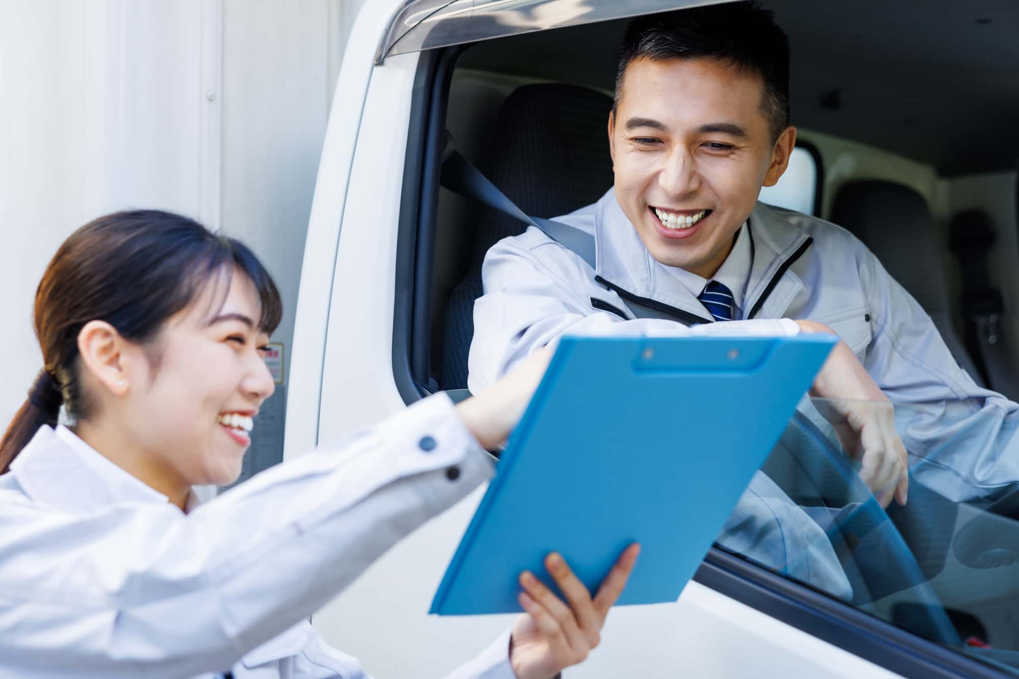 資料を見ながら会話するトラックのドライバーとビジネスパーソン