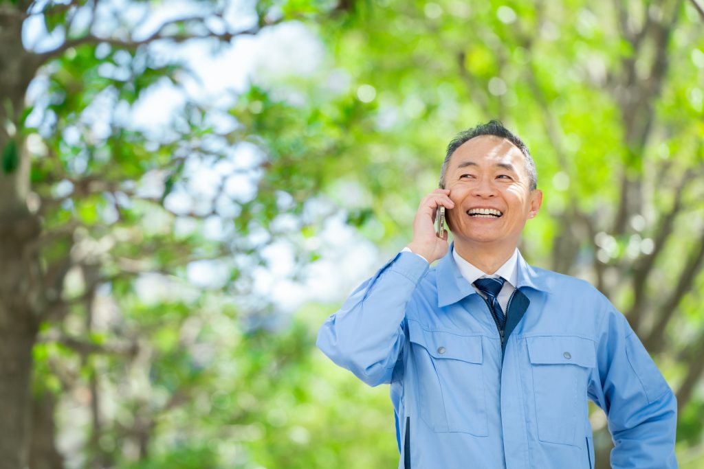 笑顔で電話する作業着を着たビジネスパーソン