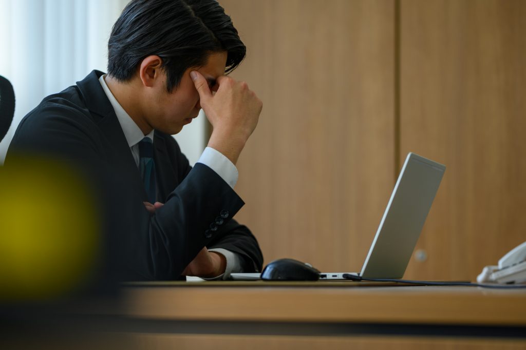 パソコンを開きながら悩むビジネスパーソン