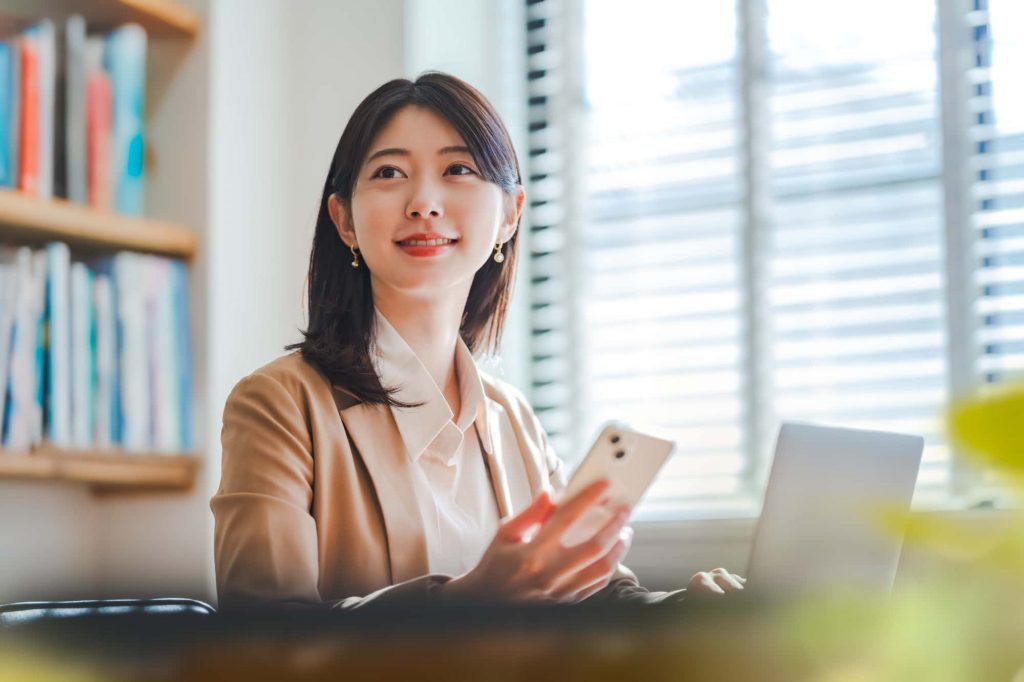 スマートフォンを片手にほほ笑むビジネスパーソン