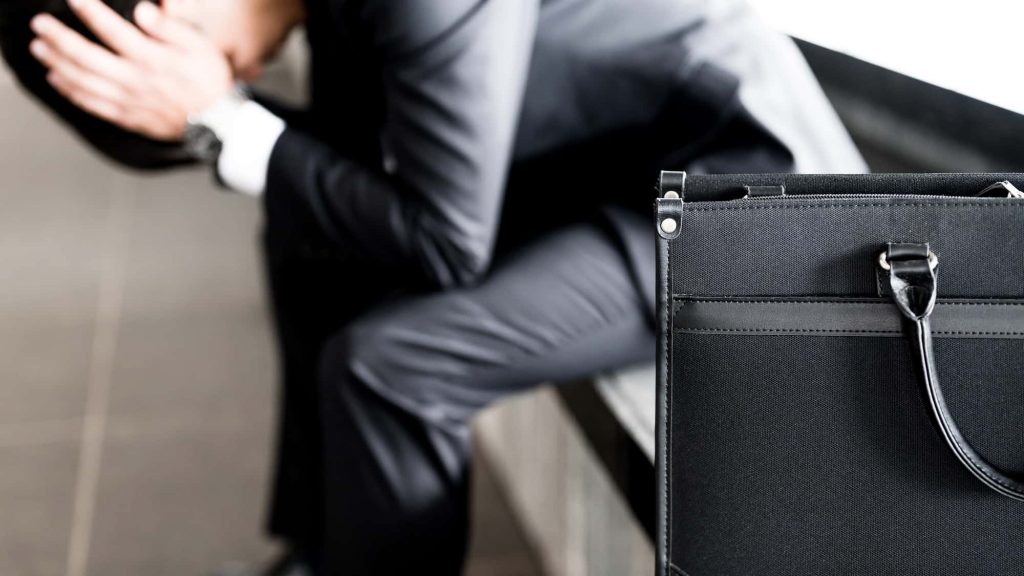 頭を抱えて落ち込むビジネスパーソン